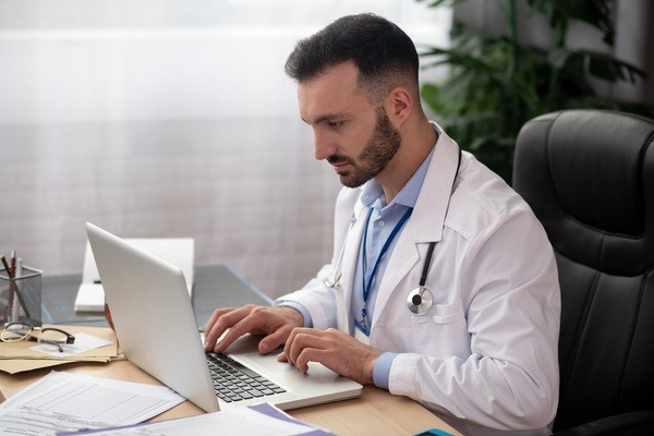 Un homme médecin en blouse derrière son ordinateur